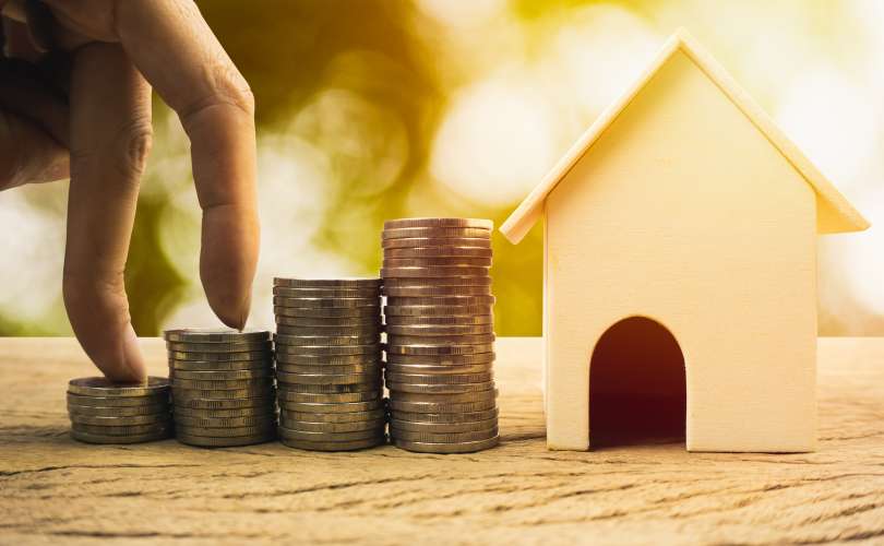 Real estate investment, home loan, savings to buy home concepts. House wooden model , Fingers climb on coins. depicts a funding or growing money for real estate investment.